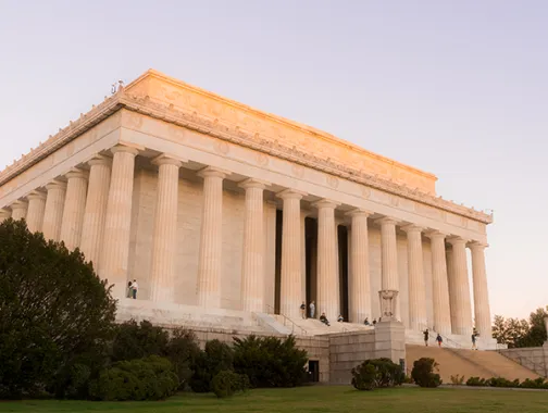 A view of the Lincoln Memorial at an angle with the sunlight at dawn.